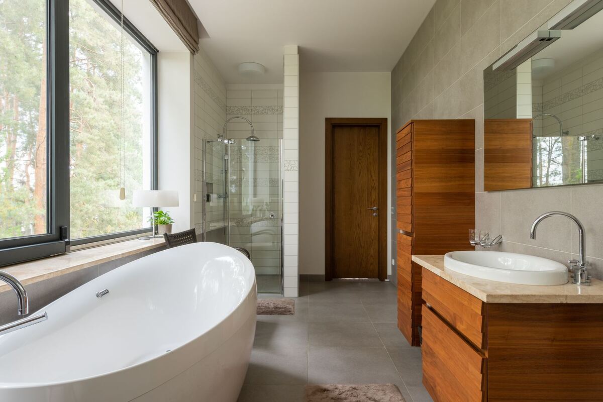 Gerenoveerde badkamer met houten wastafelmeubel en ligbad